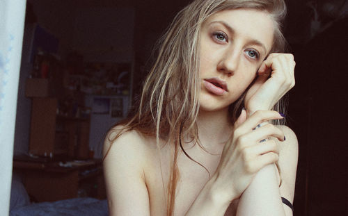 Close-up of young shirtless woman looking away at home