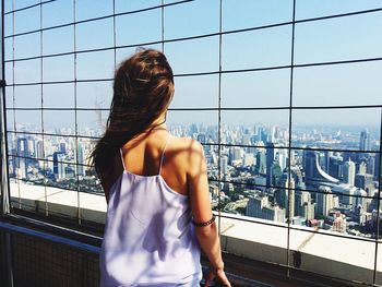 Rear view of woman standing by railing against river