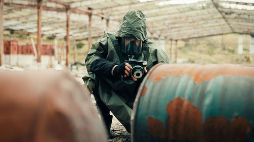 Man with gas mask photographs the radioactive barrels