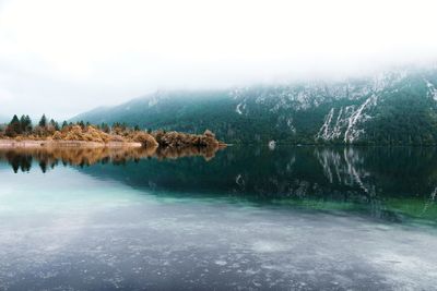 Scenic view of lake by mountains against sky