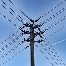 Low angle view of power lines against clear blue sky