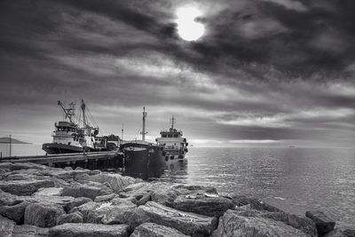 Boats in sea against cloudy sky