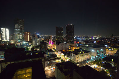 Illuminated buildings in city against sky at night