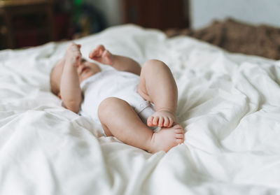 Cute baby girl 2-4 month on bed with white linen, natural tones, selective focus