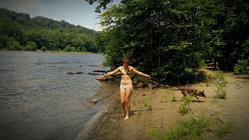 Young woman in bikini standing at riverbank