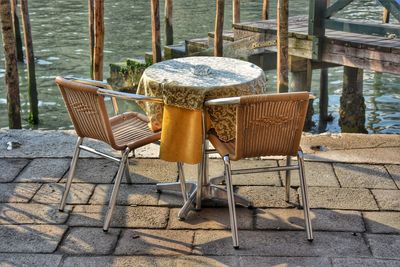 Empty chairs and table by bench