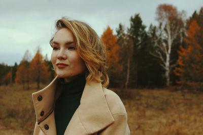 Young woman looking away while standing in forest