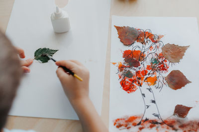 Midsection of woman holding autumn leaves on table