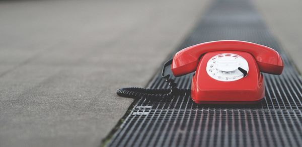 Abandoned old red rotary phone on metallic gutter lid