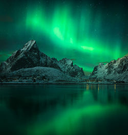 Scenic view of lake and snowcapped mountains against sky at night