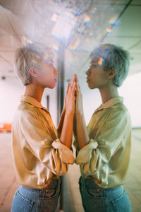 Side view of woman standing in front of glass with reflection