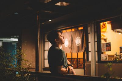 Side view of young woman in illuminated room