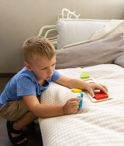 Cute boy playing with toy by bed