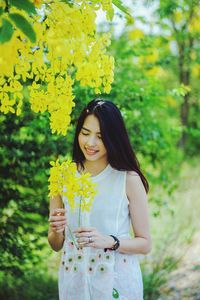 Young woman holding yellow flower