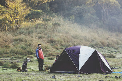 Man standing by camping tent with female friend on grassy land