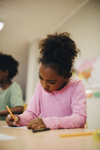 Boy writing at desk in elementary classroom