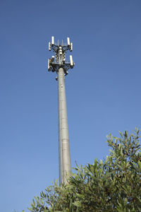 Low angle view of communications tower against clear blue sky