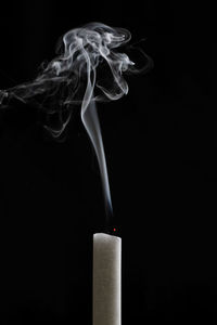 Close-up of emitting smoke against black background