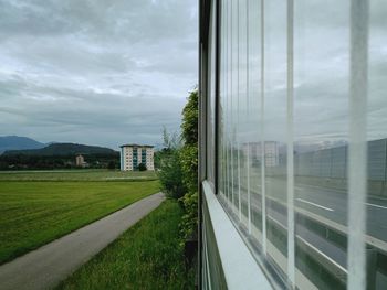 Street amidst field seen through window of building