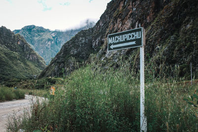 Information sign on field against mountains