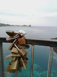 Close-up of padlocks on railing against sea