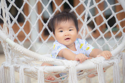 Portrait of cute baby girl behind fence