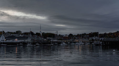 Sailboats moored in harbor against buildings in city