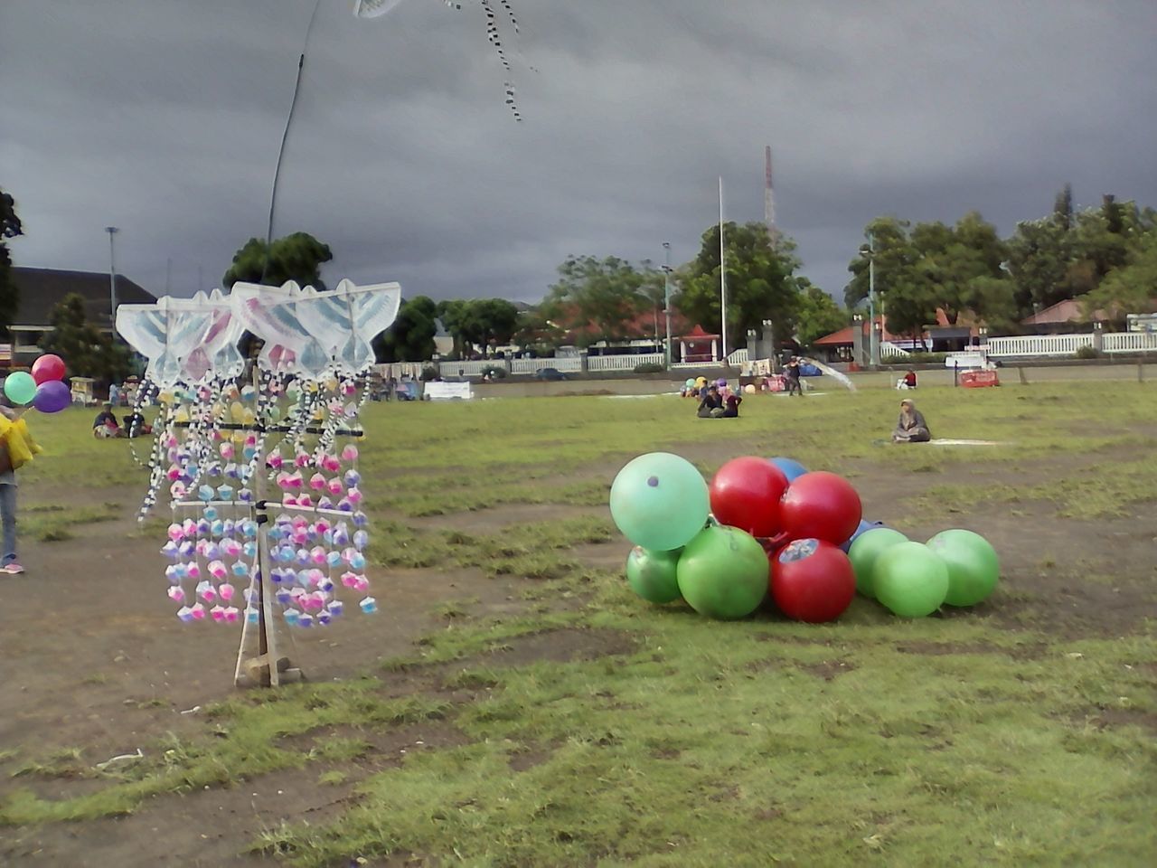 COLORFUL BALLOONS ON FIELD AGAINST SKY