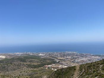High angle view of townscape by sea against blue sky
