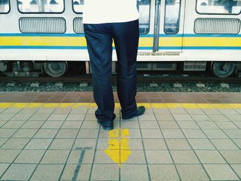 Low section of man standing on railroad station platform