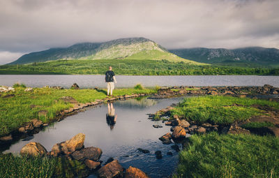 Travel and lifestyle concept, backpacker hiker reflected in lough inagh, mountains, galway, ireland 