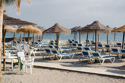 Lounge chairs on beach against sky