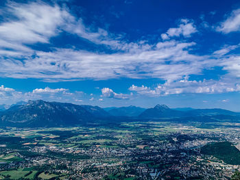 Aerial view of townscape and mountains against blue sky. 