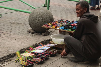 Rear view of man sitting on footpath