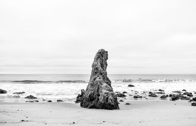 Rock on beach against sky