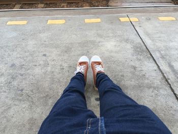 Low section of man sitting at railroad station platform