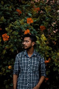 Thoughtful young man standing against plants