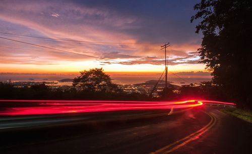 Light trails on road against sky at night