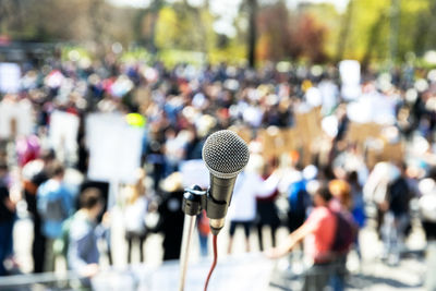 Protest or public demonstration, focus on microphone, blurred crowd of people in the background