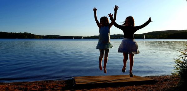 Full length of women standing at lake against sky