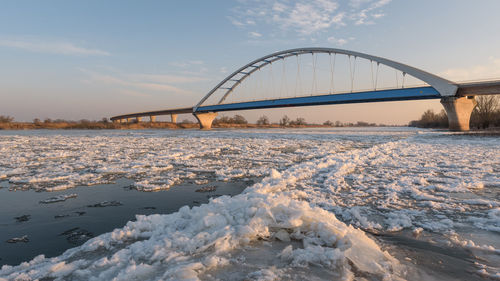 Bridge over river against sky during winter