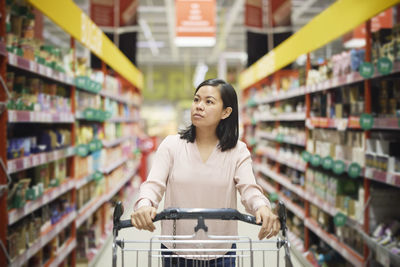 Woman looking at prices during inflation while doing shopping in supermarket