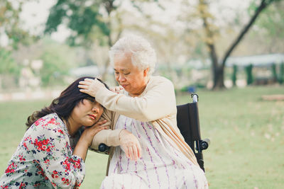 Woman resting head on mother shoulder in park