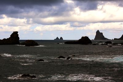 Scenic view of beach against cloudy sky