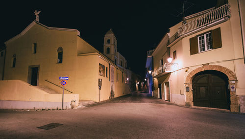 Empty road amidst buildings in city at night