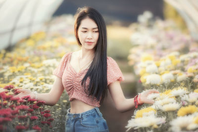 Beautiful young woman standing by flower in store