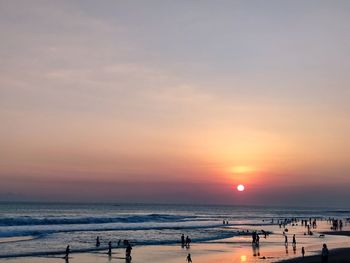 People on beach against sky during sunset