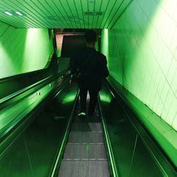 Rear view of man walking on escalator