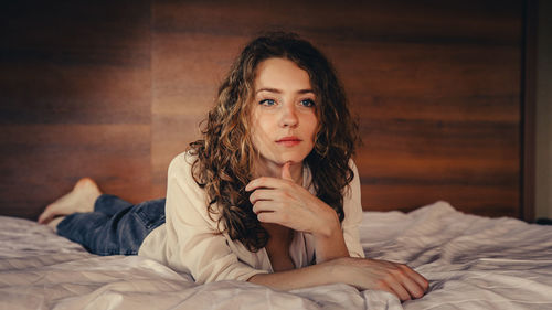 Portrait of young woman sitting on bed at home