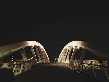 Illuminated road against clear sky at night
